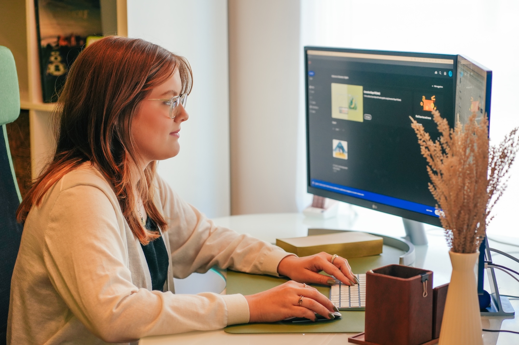A designer working on her two monitors at her desk.