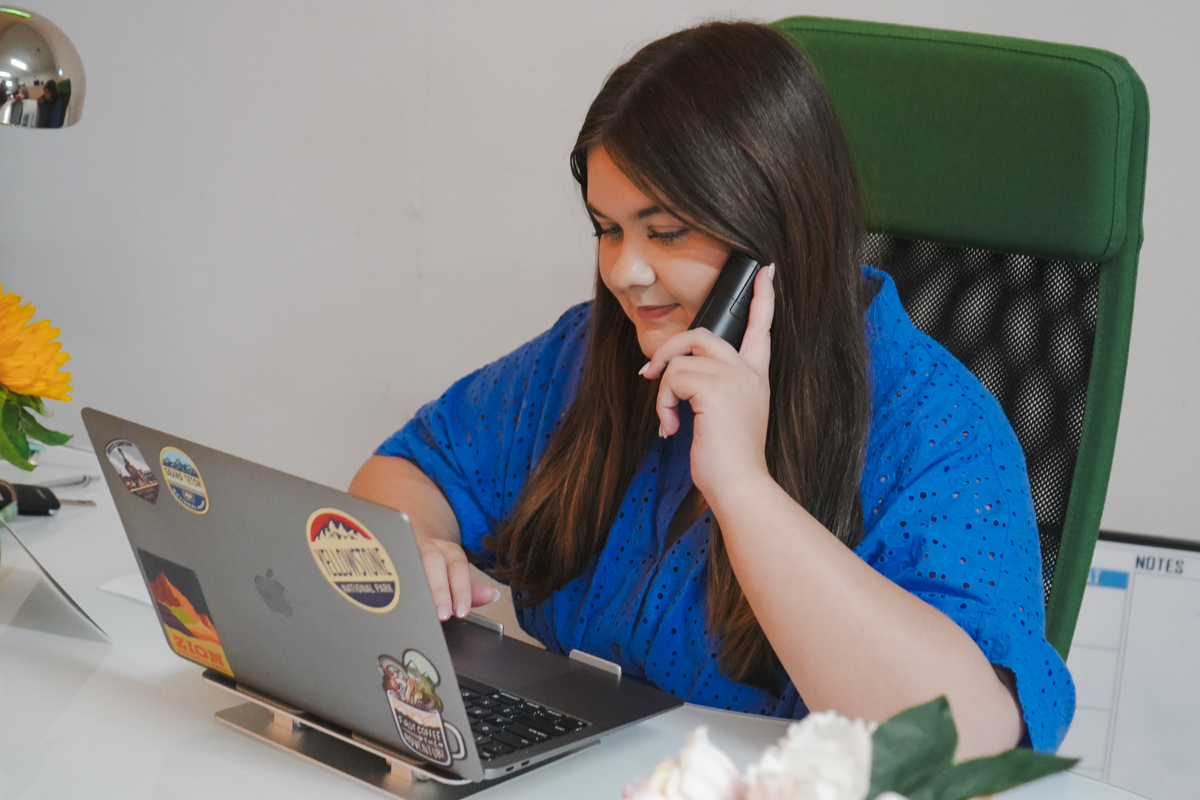 Marketing stategy specialist sitting at her desk working on her computer and answering the phone.